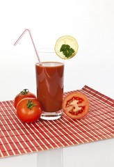 Tomato juice in a glass with tomatoes and lemon