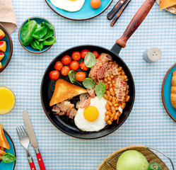 Fried eggs, bacon, tomatoes, beans and spinach in pan