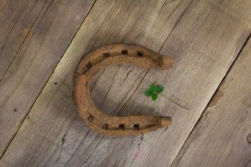 Lucky four-leaf clover and horseshoe on wooden background
