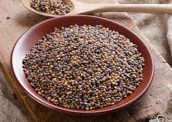 Dry Organic Brown Lentils in bowl on a old wooden board