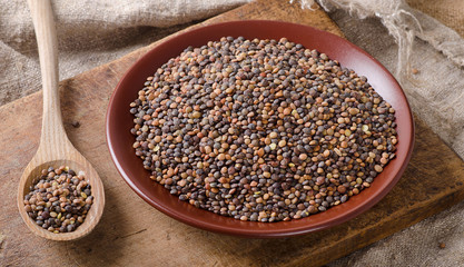Dry Organic Brown Lentils in bowl on a old wooden board