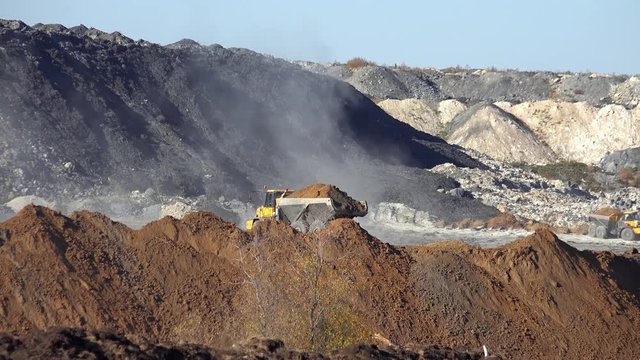 Haul trucks BelAZ conceal ground on open coal quarry Urgunsky in Iskitim District of Novosibirsk Region