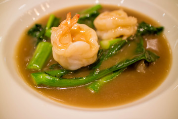 Fried noodle with prawn, chinese kale and gravy on white plate