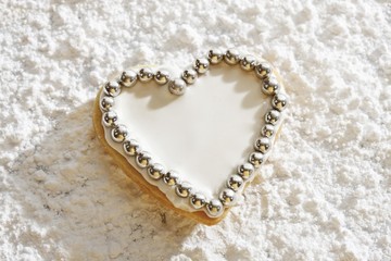 Heart-shaped short pastry cookies, covered with sugar coating and silver sugar pearls, on icing sugar