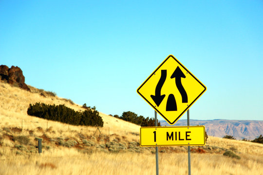 devided highway begins sgin in Route 66 in state of Nevada, with weeds and rocks as background