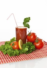 Tomato juice in a glass with tomatoes, lemon and parsley