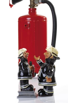 Miniature figures of fire fighters in front of a fire extinguisher