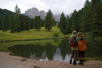 Mother and child at a small lake on the Seceda High Plateau with a view towards the Geisler mountains, Puez-Geisler National Park, Wolkenstein, Alto Adige, Italy, Europe
