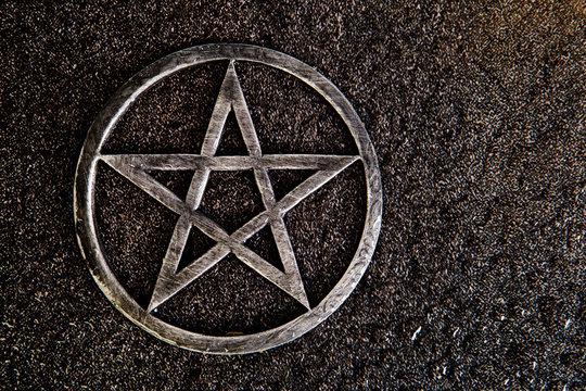Gray metal pentagram on slate background with water drops