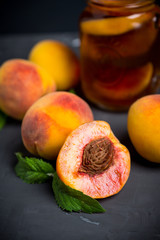Jar of peach iced tea with fresh peaches on the rustic background. Shallow depth of field.