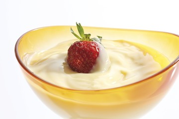 Vanilla pudding and a strawberry in a glass bowl