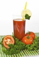 Tomato juice in a glass with tomatoes, lemon and parsley