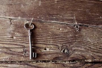 Old key hanging on a rustic wooden wall