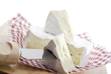 Soft cheese on waxed paper and a cheese knife