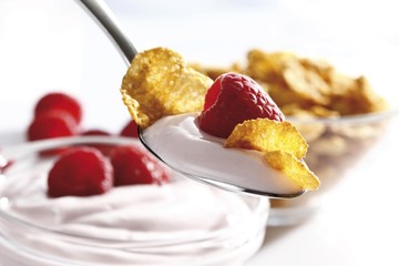 Raspberry yoghurt with cornflakes on a spoon