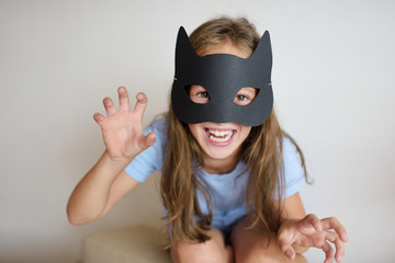The girl plays in a self-made mask of black cat 