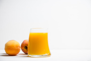 Glass of peach juice with fresh peaches on the rustic background. Shallow depth of field.