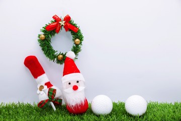 Obraz na płótnie Canvas Santa with Christmas wreath and golf ball on green grass