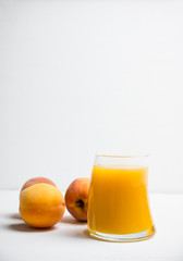 Glass of peach juice with fresh peaches on the rustic background. Shallow depth of field.
