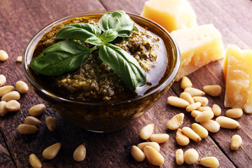 Pesto genovese - traditional Italian green basil sauce with pine nuts, basil on rustic wooden background.