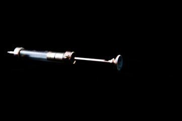 Old syringe without a needle isolated on black.