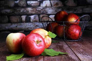 Ripe red apples with leaves on wooden background