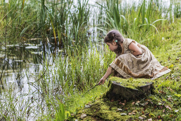 A little girl playing at a beautiful pond