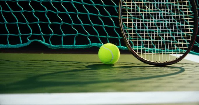Tennis ball and racket against net in court 