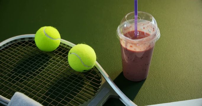 Milkshake and sports equipment in tennis court 
