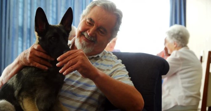 Senior man petting his dog at retirement home 