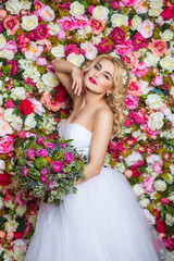 beautiful woman posing in wedding dress flowers wall background