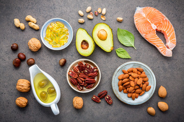 Selection food sources of omega 3 and unsaturated fats. Superfood high vitamin e and dietary fiber for healthy food. Almond ,pecan,hazelnuts,walnuts,olive oil,fish oil and salmon on stone background.