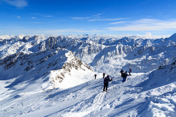 Naklejka na ściany i meble Group of people hiking on snowshoes and mountain snow panorama with blue sky in Stubai Alps, Austria