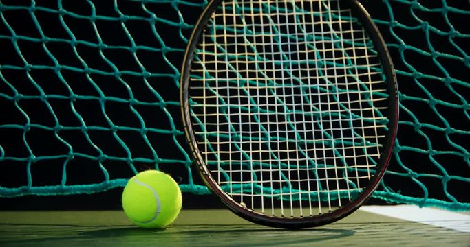 Tennis ball and racket against net in court 