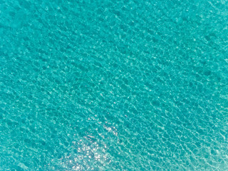 Aerial top view of sea surface. Transparent turquoise ocean water surface from drone.