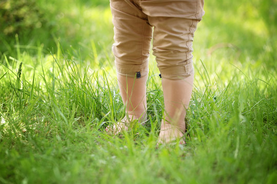 Little child walking on green grass in park