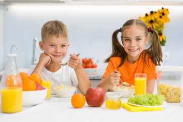 Happy brother and sister breakfast with cornflakes and milk in the kitchen