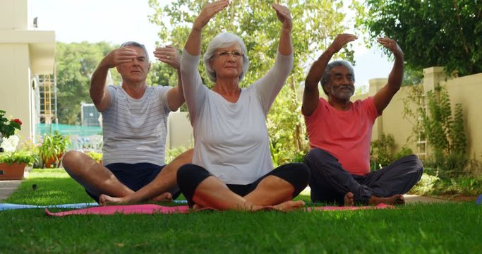 Senior friends performing yoga in garden 