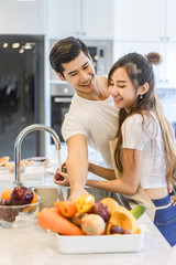 Beautiful asian young couple is looking to cooking in kitchen at home.