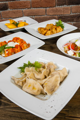 Set of different salads, dumplings and ravioli on a wooden table
