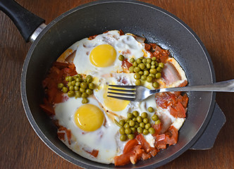 Scrambled eggs with ham and tomatoes, green peas