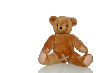Sad teddy bear with a plaster in the genital area, symbolic image for abuse