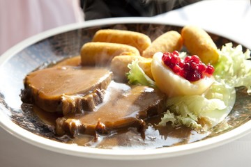 Roast pork with sauce, potato croquettes and pear with cranberries