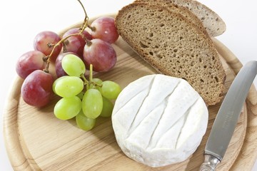Chardonnay cheese on a board with grapes and bread