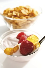 Raspberry yoghurt with cornflakes on a spoon