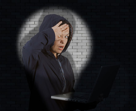 Criminal Woman Hacker Wearing Hood On Using a Laptop Catched with Flashlight