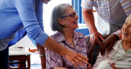 Senior friends and female doctor stroking kitten at retirement home - Powered by Adobe