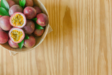 Passion fruit in wood bowl on wood table in top view flat lay with copy space for background or wallpaper. Ripe passion fruit so sweet and sour suitable make dessert. Passion fruit is tropical fruit.