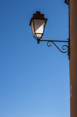 Fototapeta na wymiar Bonifacio, Corsica: arredo urbano e architettura cittadina, un lampione in ferro battuto e un cielo azzurro sullo sfondo