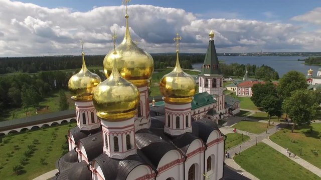 Fast flight aroud golden domes Valday Iversky Russian Orthodox Monastery. Valdaysky National Park UNESCO Biosphere Reserve Lake Seliger. Aerial drone. Beautiful nature summer clouds horizon.